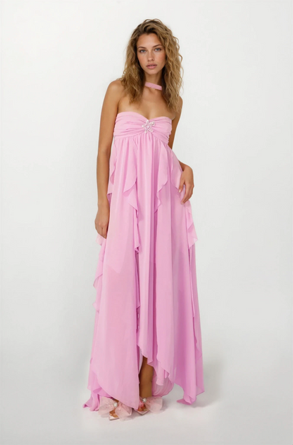Front view of a women's pink strapless ruched ruffle maxi dress with a starfish brooch and a high-low hem, on a white background.
