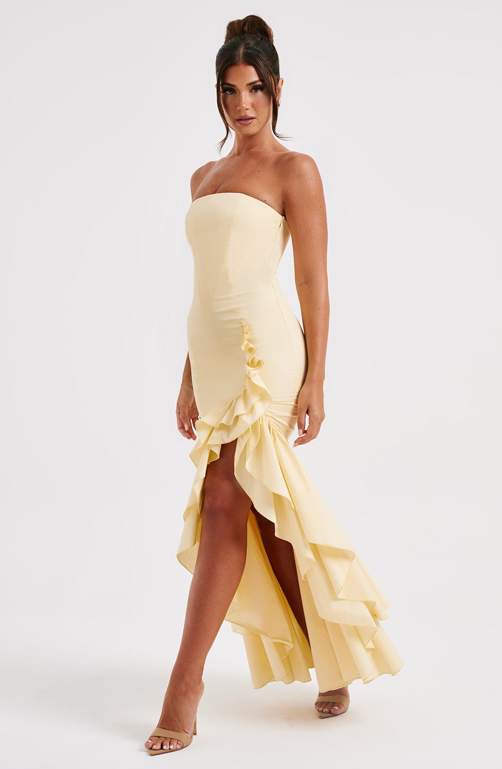 Front view of a women's strapless ruffle high-low maxi dress in a soft yellow, showcasing the elegant ruffles and thigh-high slit.
