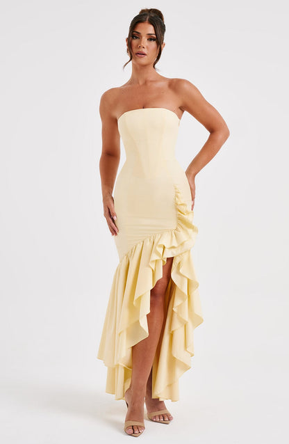 Light yellow strapless ruffle high-low maxi dress featuring a structured bodice and flowing skirt with ruffles.