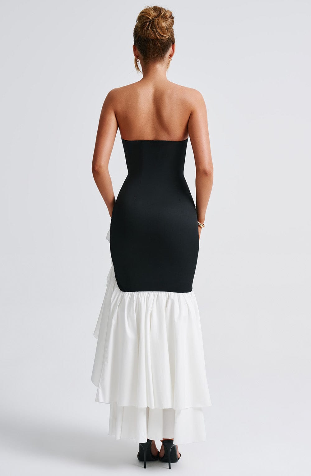 Back view of the black and white strapless ruffle high-low maxi dress, showing the layered white skirt.