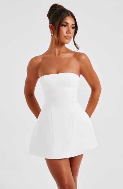 Front view of a woman wearing a white strapless seamed bubble mini dress with a fitted bodice and flared skirt.