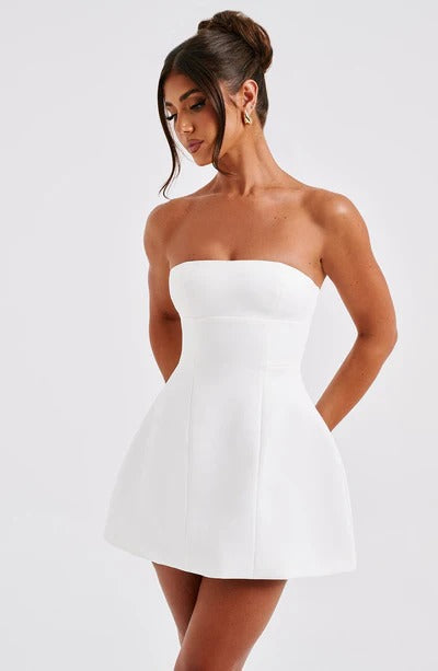 Slightly angled view of a white strapless bubble mini dress, showcasing the seamed details and structured silhouette.