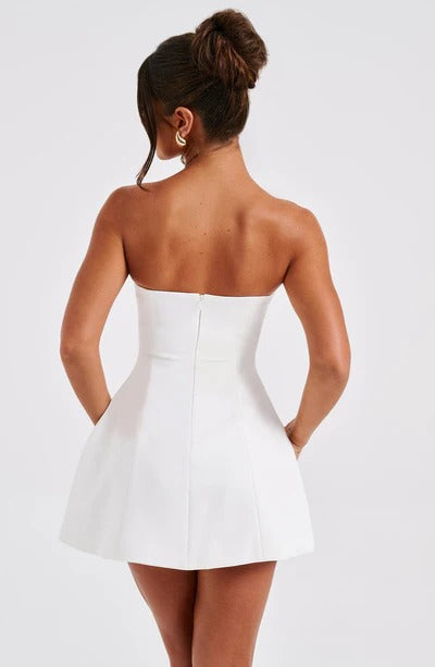Back view of a white strapless seamed bubble mini dress, highlighting the hidden zipper closure and short length.