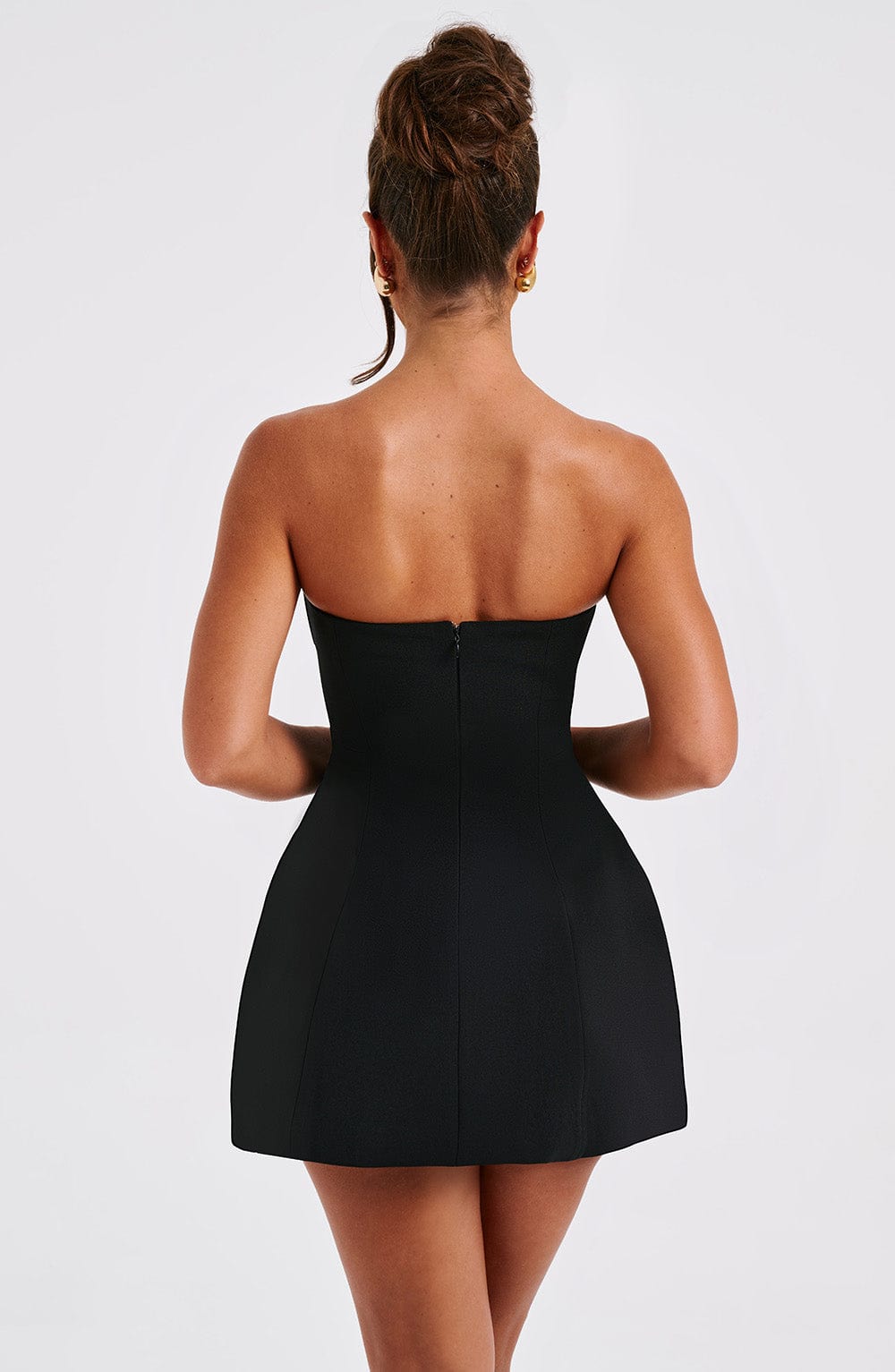 Back view of a black strapless seamed bubble mini dress, showing the zipper and fitted back.