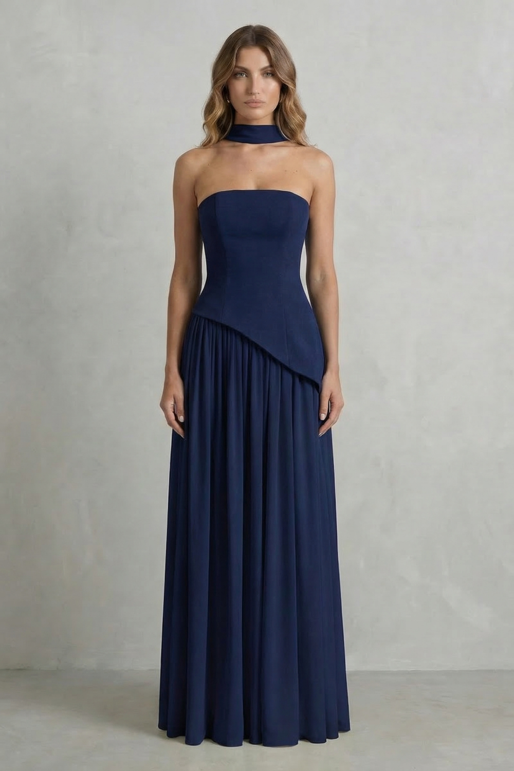 Full-length view of a navy blue strapless maxi dress, showcasing the draped top and a graceful pleated skirt, a chic vacation dress.
