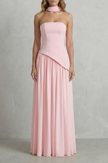 Full-length light pink strapless maxi dress with draped neck detail and asymmetric bodice, suitable for elegant events or as a vacation dress.