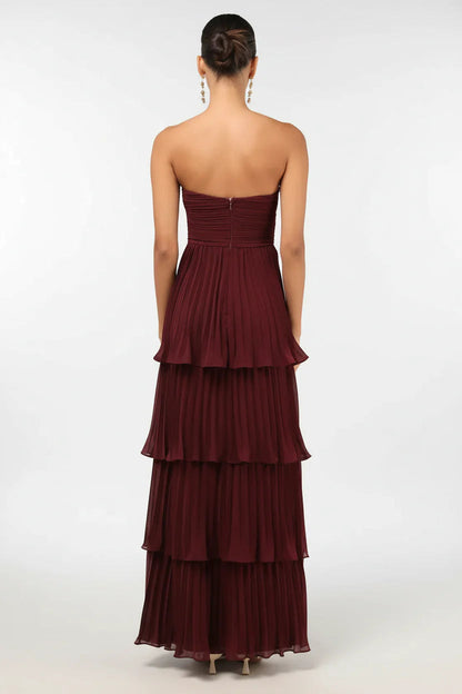 Back view of the elegant burgundy strapless tiered pleated maxi dress, showcasing the flowing skirt.