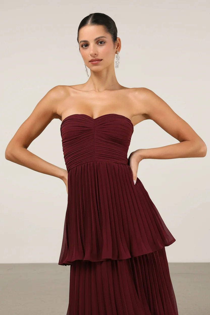 Close-up of the bodice and upper tiers of the burgundy strapless pleated maxi dress, showing ruched detail.