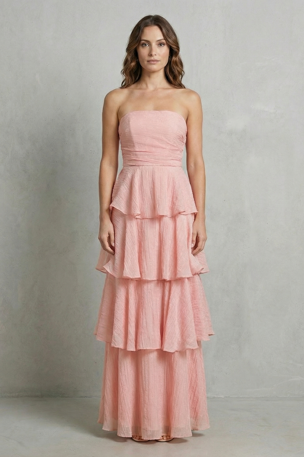 Front view of a woman in a soft pink strapless tiered ruffle maxi dress, showcasing the tiered design.
