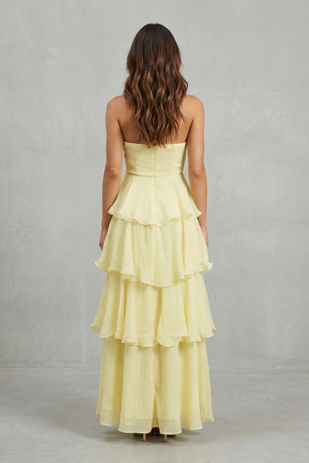Back view of the light yellow strapless tiered ruffle maxi dress, highlighting the layered skirt.