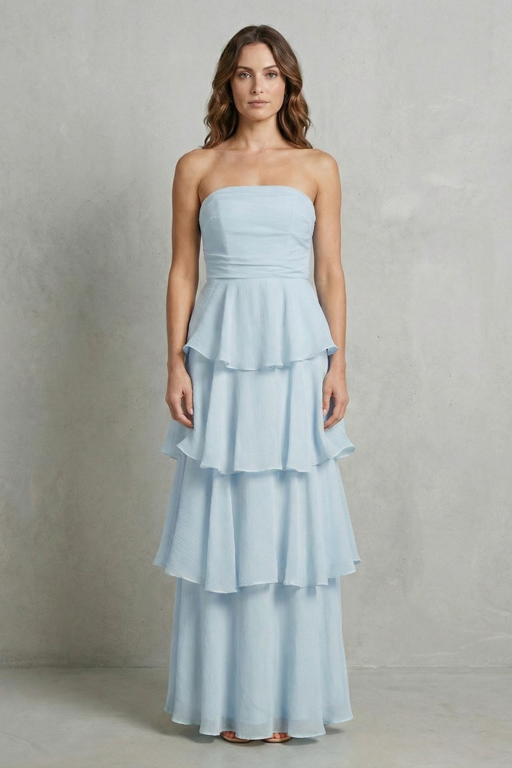 Front view of a woman in a light blue strapless tiered ruffle maxi dress, with a delicate tiered skirt.