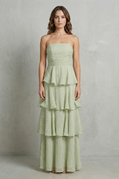 Front view of a woman wearing a sage green strapless tiered ruffle maxi dress, with soft ruffles.