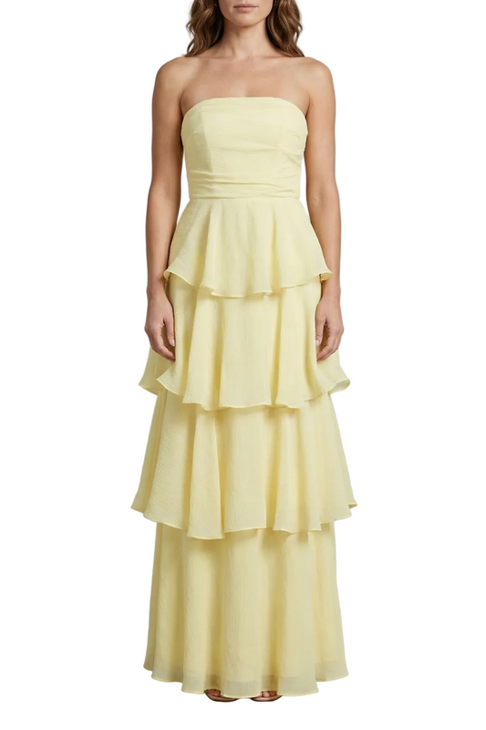 Full-length view of a light yellow strapless tiered ruffle maxi dress, elegant for wedding guests.