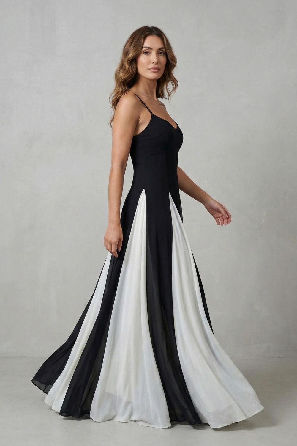 Side profile of a women's black and white strappy maxi dress, showing the movement of the paneled skirt.