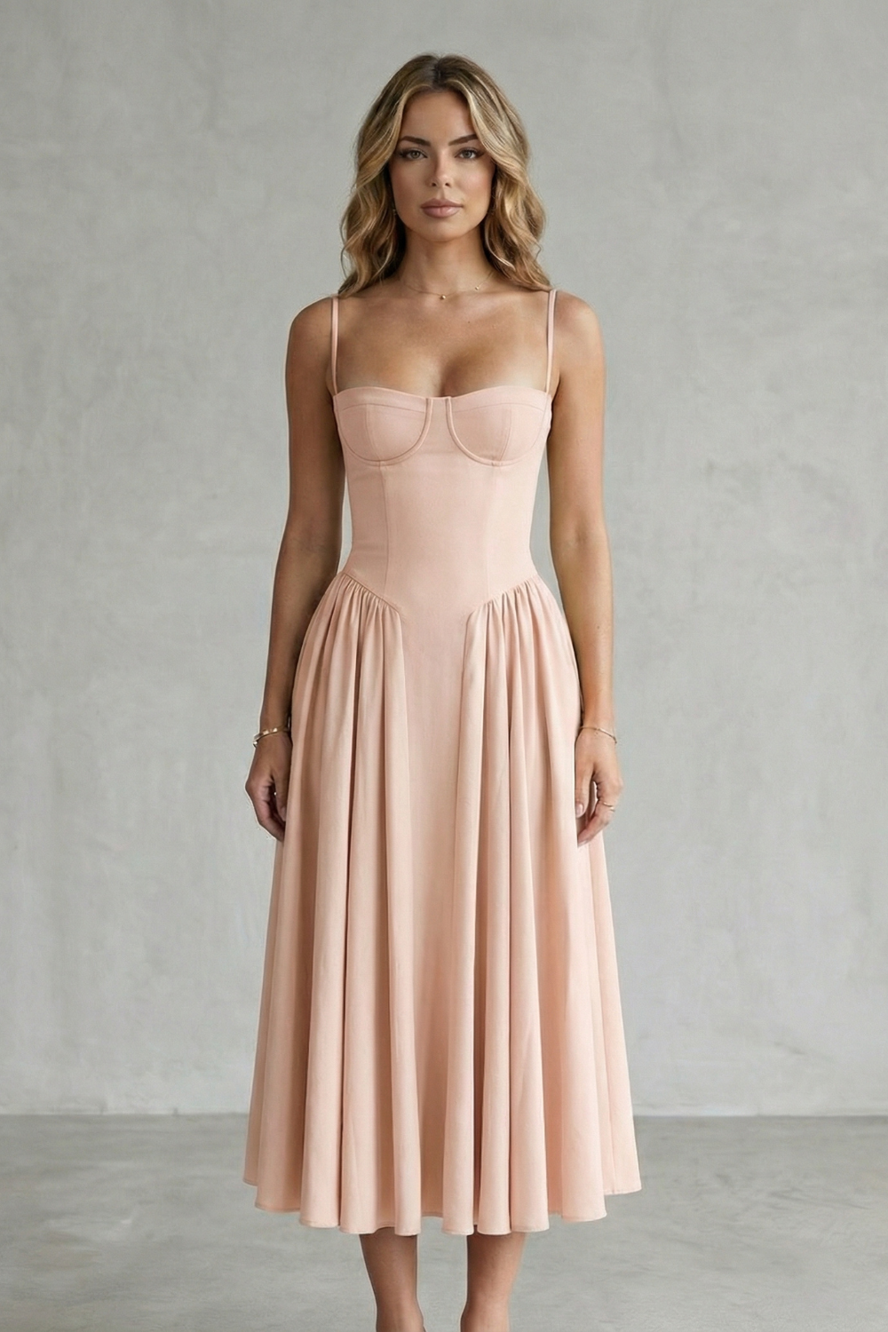 Front view of a woman wearing a soft peach strappy structured sweetheart neck midi dress, highlighting the sweetheart neckline.