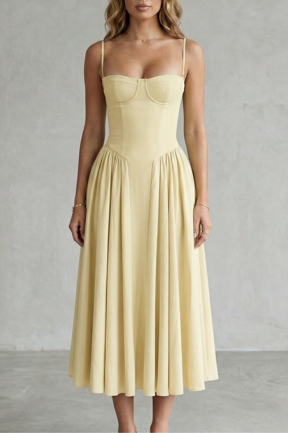 Pale yellow structured sweetheart neck midi dress with delicate spaghetti straps and a flowing pleated skirt.