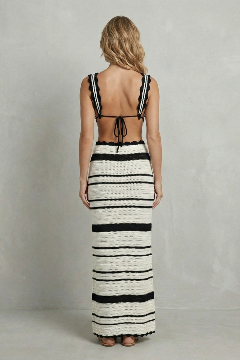 Back view of a women's striped scalloped crochet maxi skirt set with a tie-back top and long skirt.