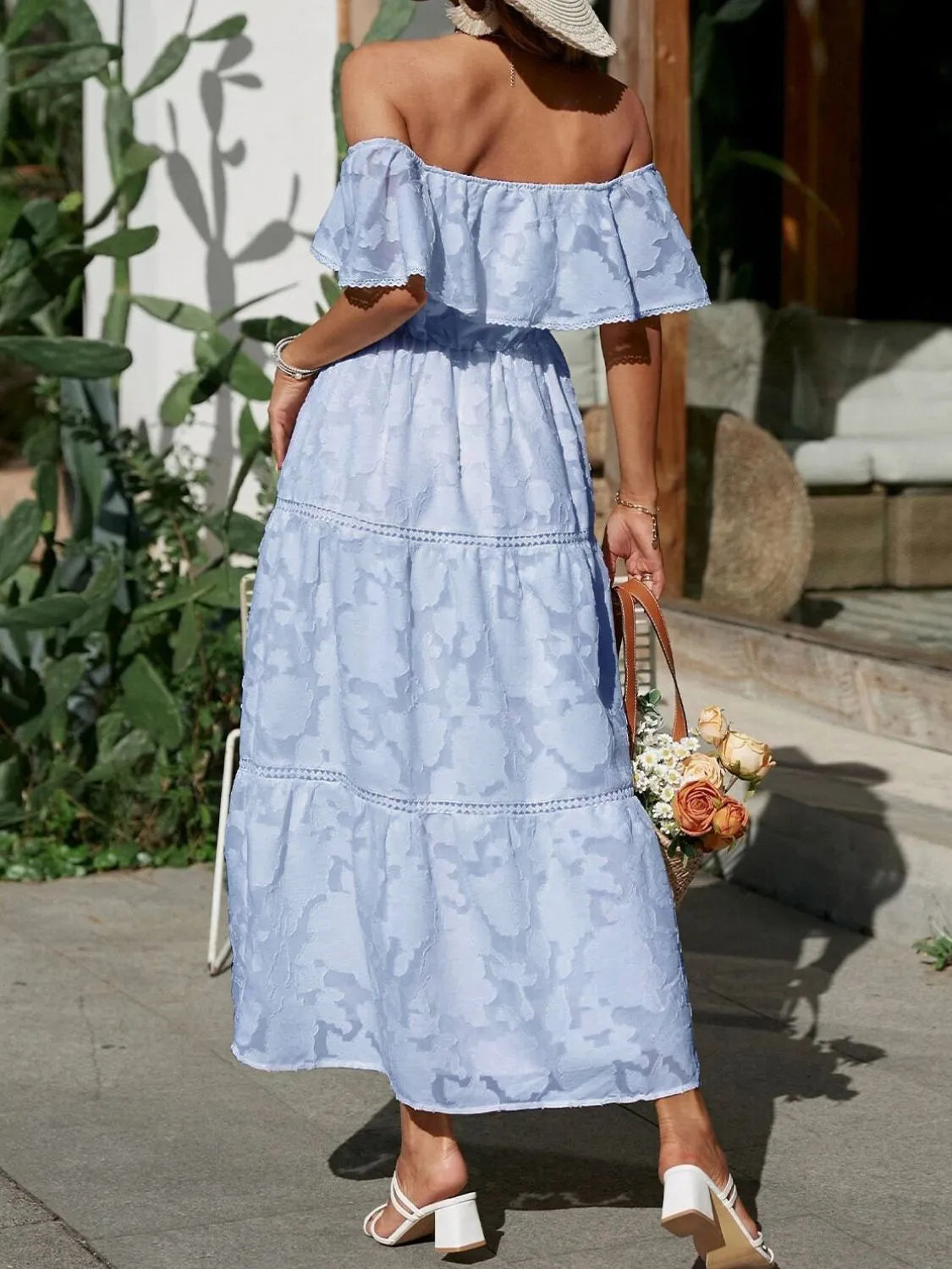 Back view of a light blue off-shoulder tiered maxi dress, showcasing the flowy silhouette and tiered skirt with delicate trim.