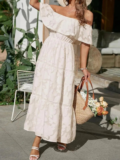Elegant off-shoulder tiered maxi dress for women in a light cream color, featuring a textured floral pattern and ruffled neckline.
