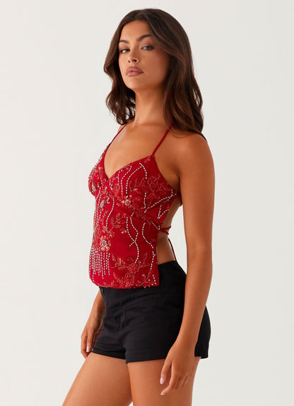 Side view of red spaghetti strap V-neck crop top with fitted waist and beaded floral pattern