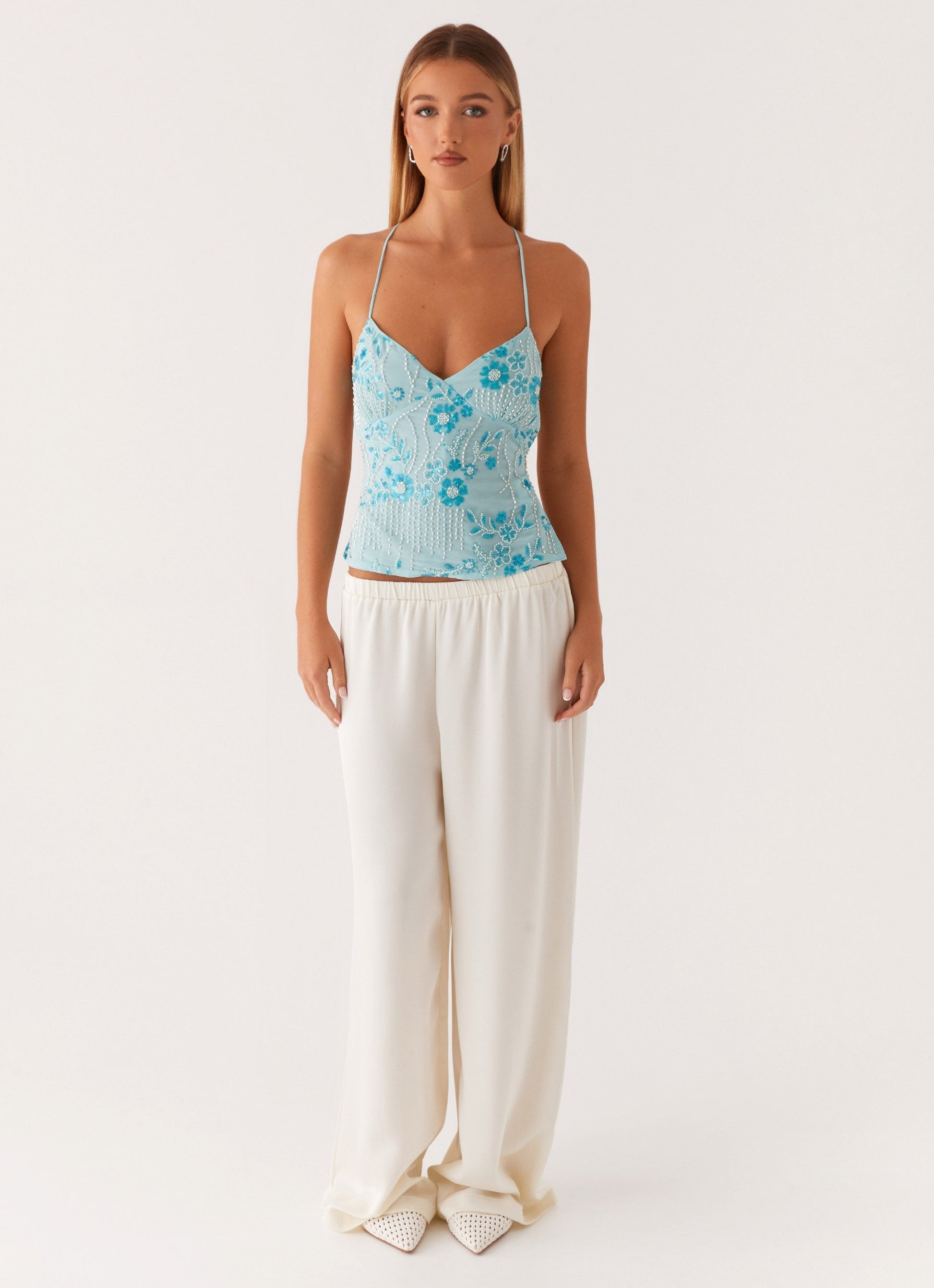 Light blue V-neck spaghetti strap crop top with embroidered floral details, front fit view