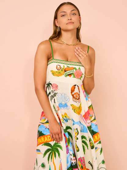 Front view of women's tropical print smocked maxi dress featuring a colorful paradise motif and green spaghetti straps.
