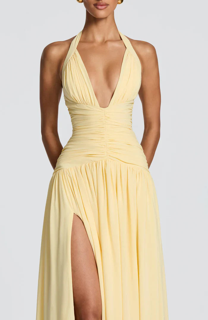 Close-up pale yellow halter maxi dress showing pleated bust, gathered waist ruching, and slit detail