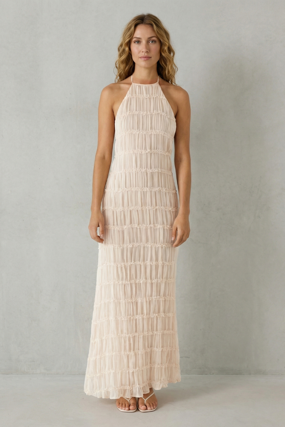 Front view of a women's light pink textured halter maxi dress, showcasing the ruched fabric and long length.