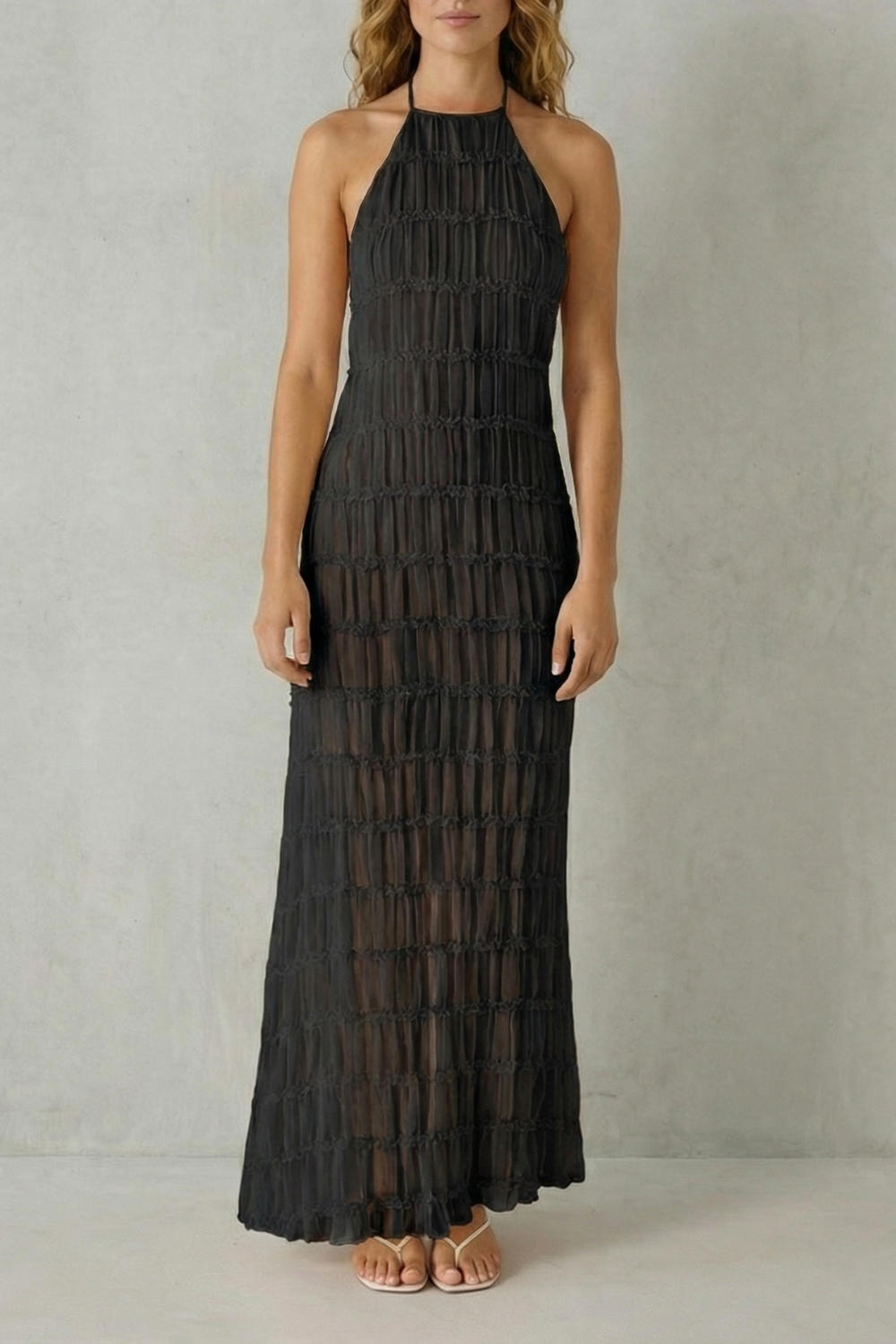 Full-length view of a black textured halter maxi dress with an open back, ideal as a vacation dress.