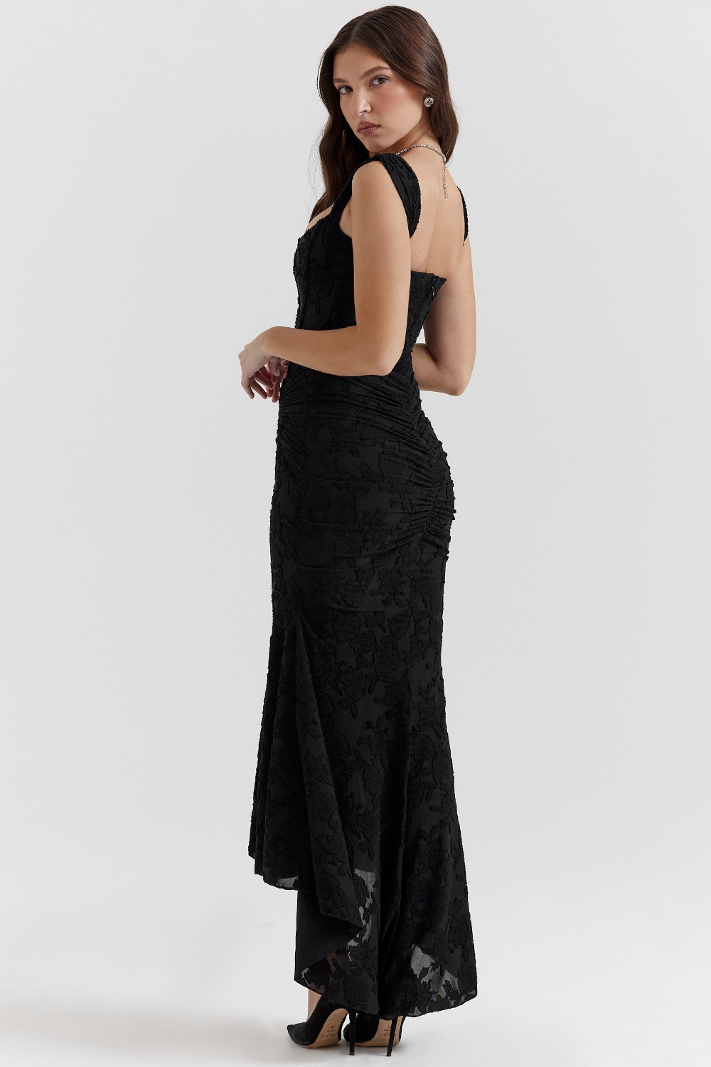 Side view of a black floral lace midi dress with a square neckline, ruched detailing, and a sophisticated high-low mermaid skirt.