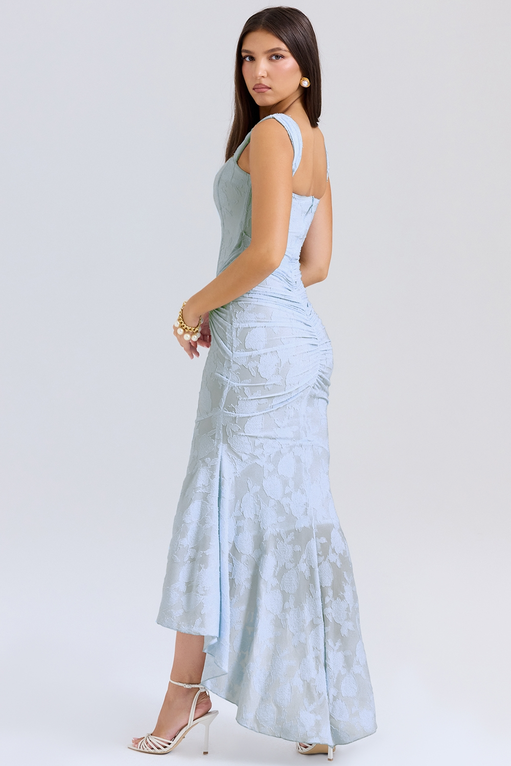 Side view of a light blue floral lace midi dress showing the ruched back and elegant high-low mermaid style, ideal for special occasions.