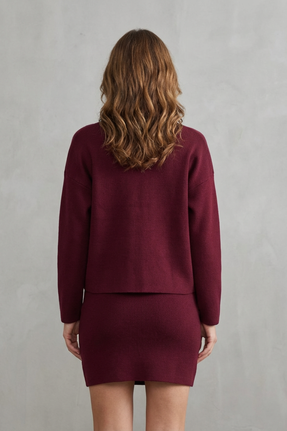 Back view of a women's maroon knit long sleeve top and a matching mini skirt set.