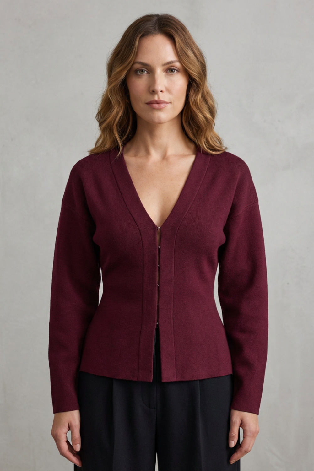 Front view of a women's maroon knit long sleeve v-neck top paired with black trousers.