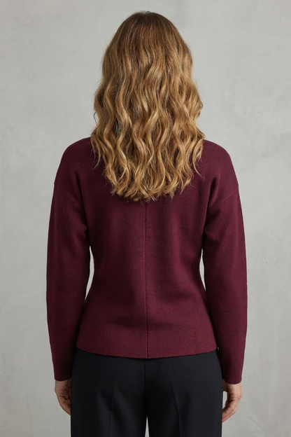 Back view of a women's maroon knit long sleeve v-neck top, worn with black trousers.