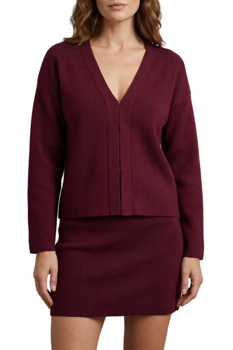 Front view of a women's maroon knit v-neck long sleeve top and matching mini skirt set.
