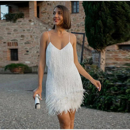 Full body shot of a white V-neck sequin feather mini dress with delicate spaghetti straps, walking outdoors.