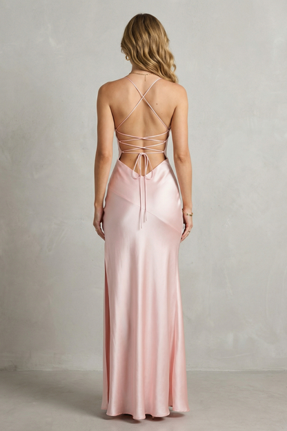 Back view of the light pink satin maxi dress, highlighting the criss-cross lace-up back detail and floor-length skirt.