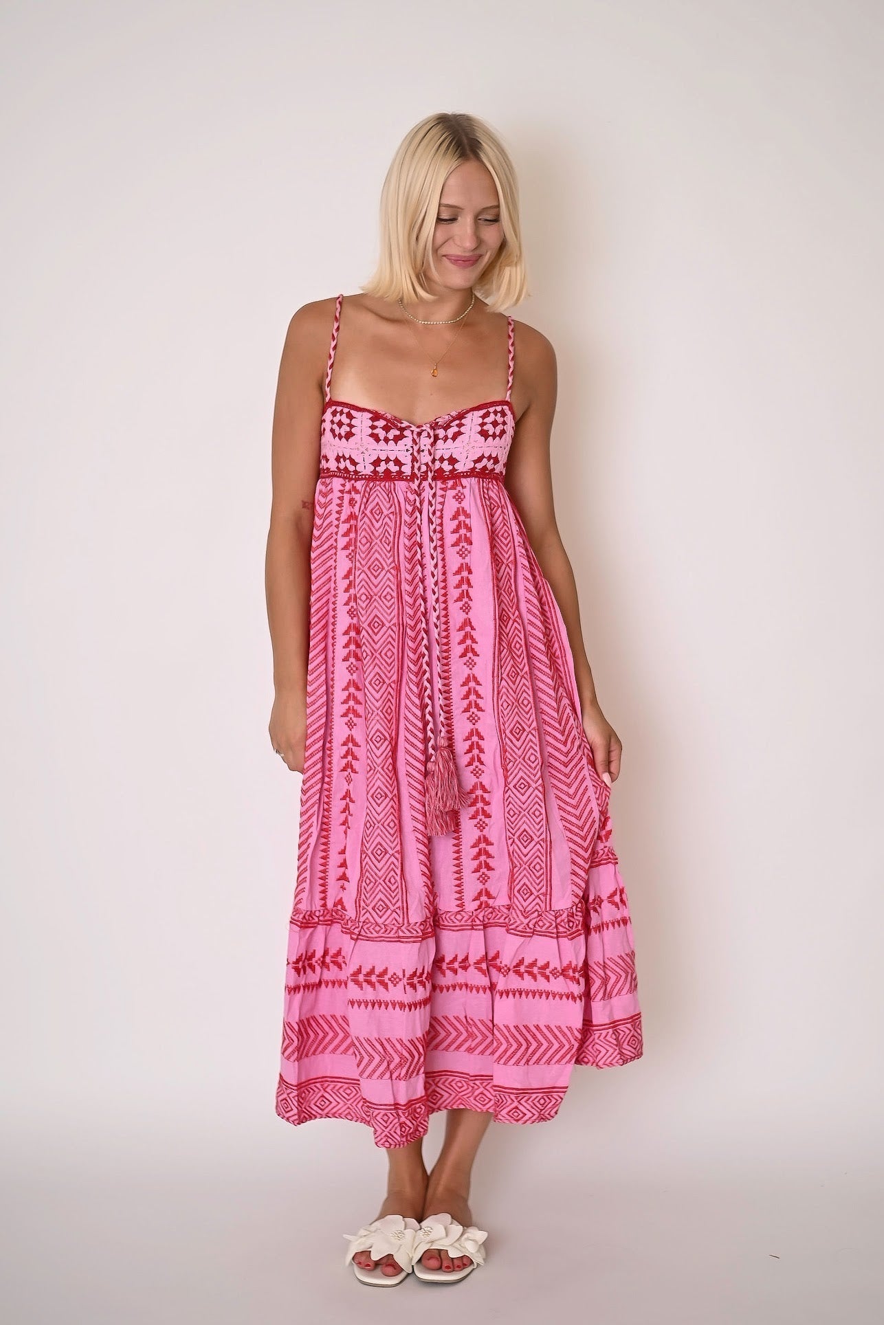 Women pink printed maxi dress with square neckline, narrow straps, front tassel tie, and tiered hem front view
