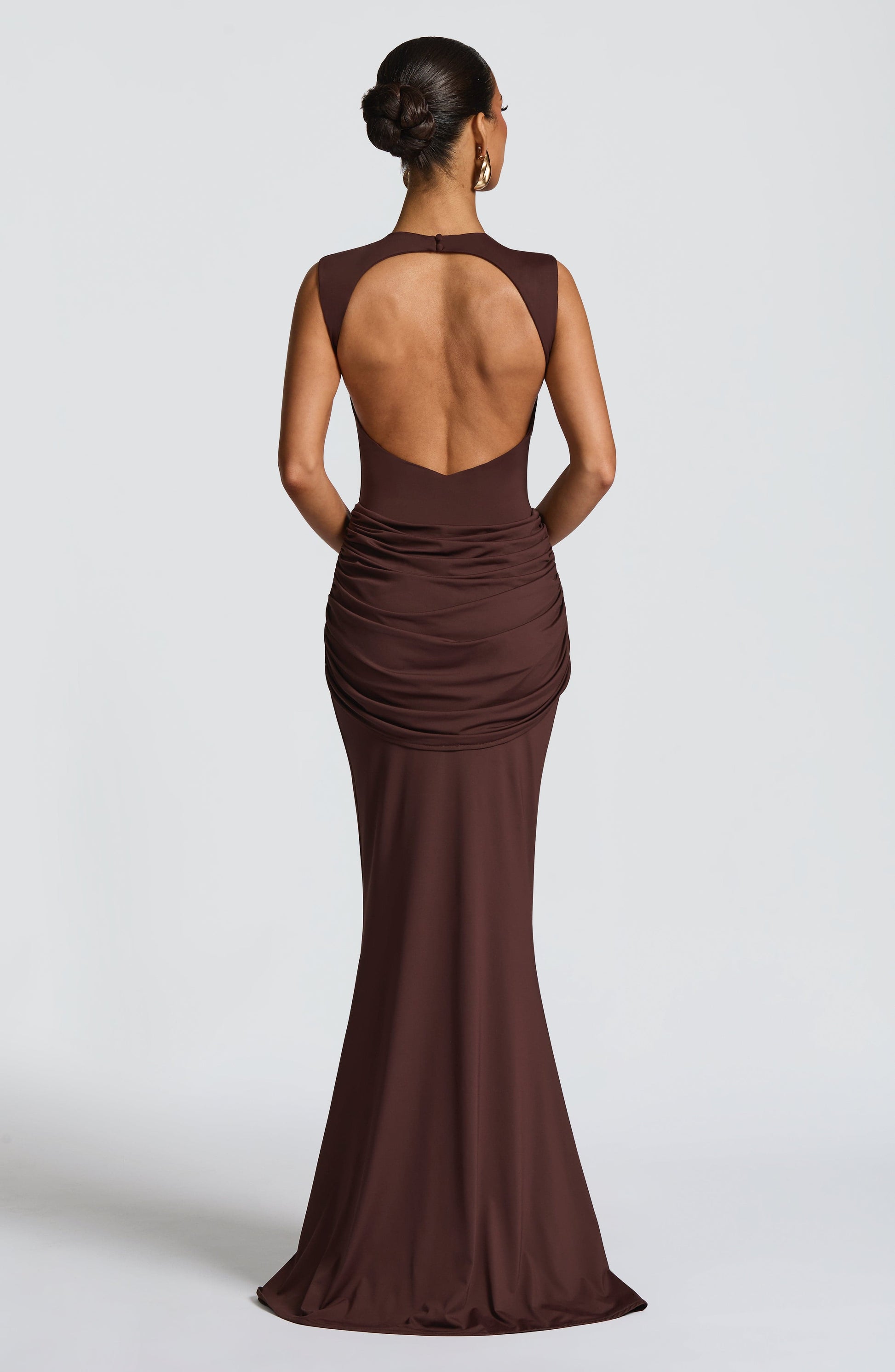 Back view of chocolate brown backless maxi dress with oval open back and ruched hip drape