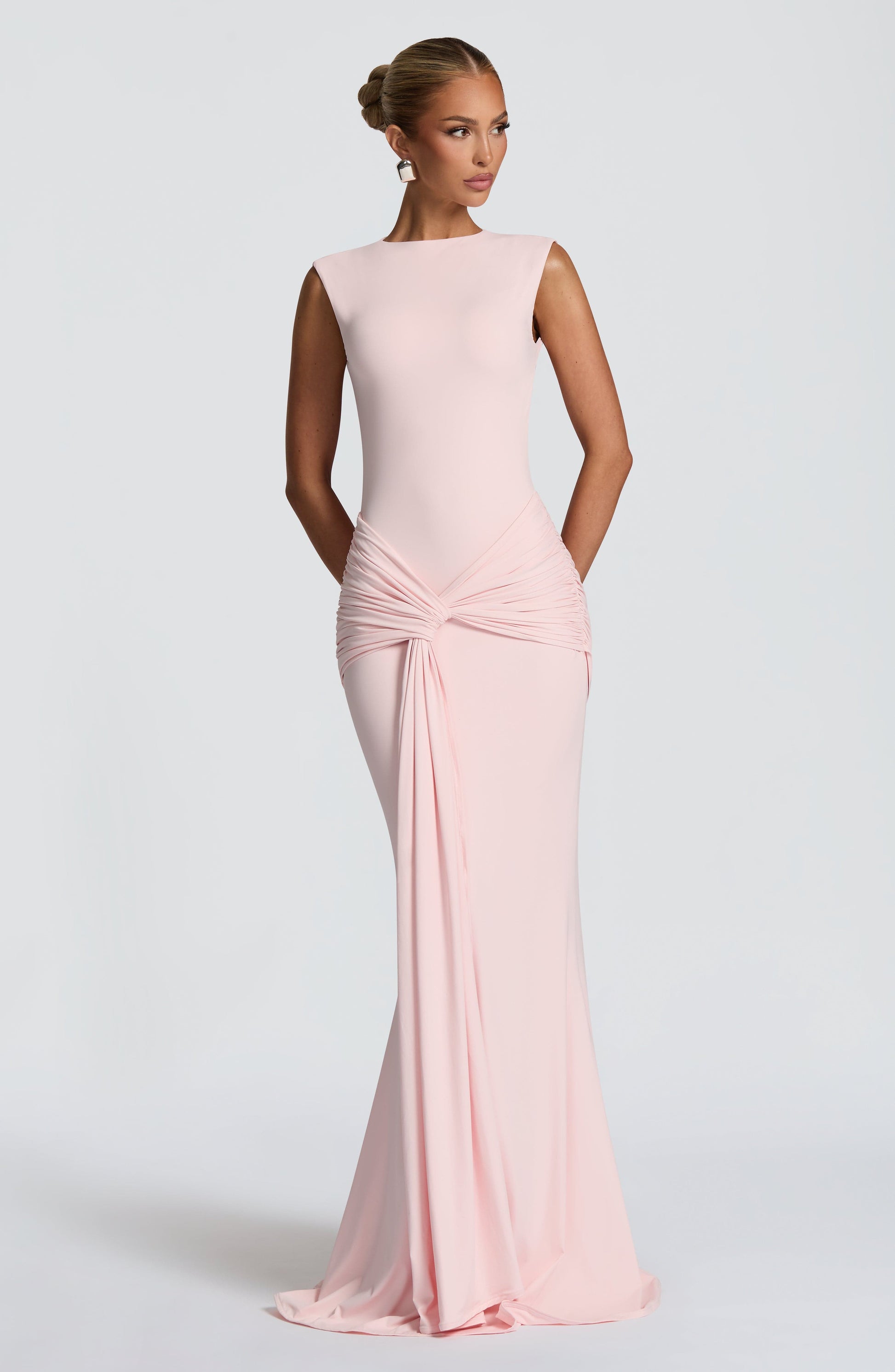 Blush pink sleeveless maxi dress, angled front view showing ruched hip detail and long drape