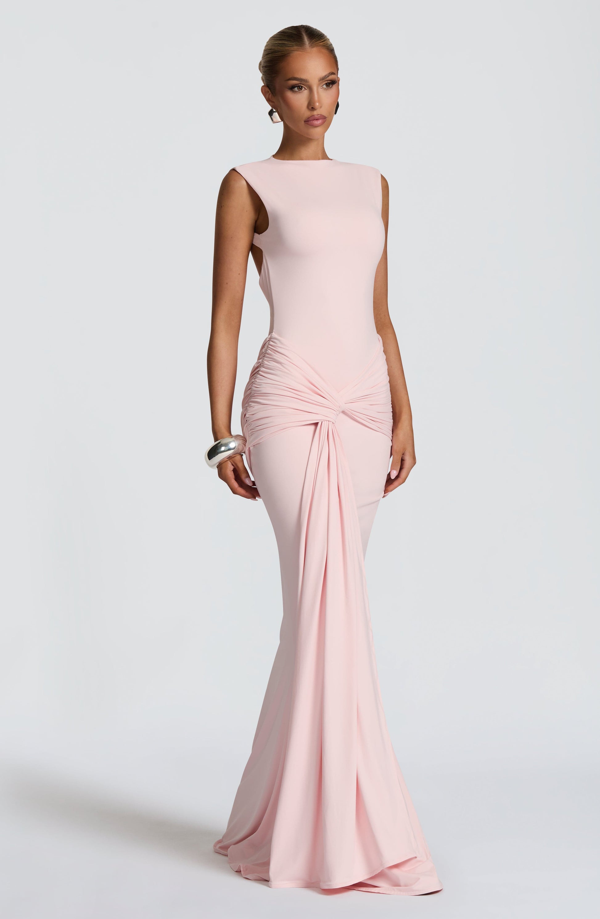 Blush pink bodycon maxi dress in three-quarter pose, highlighting ruched waist and floor-length hem