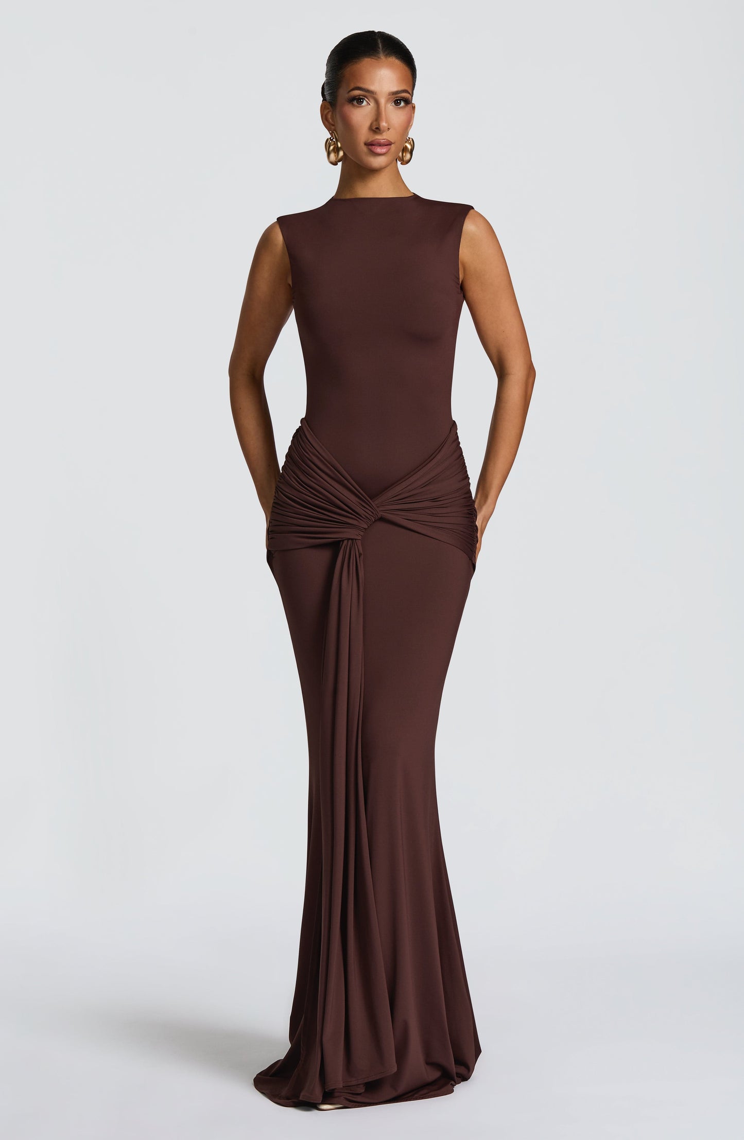 Chocolate brown sleeveless maxi dress with ruched waist knot and long draped front panel, bodycon fit
