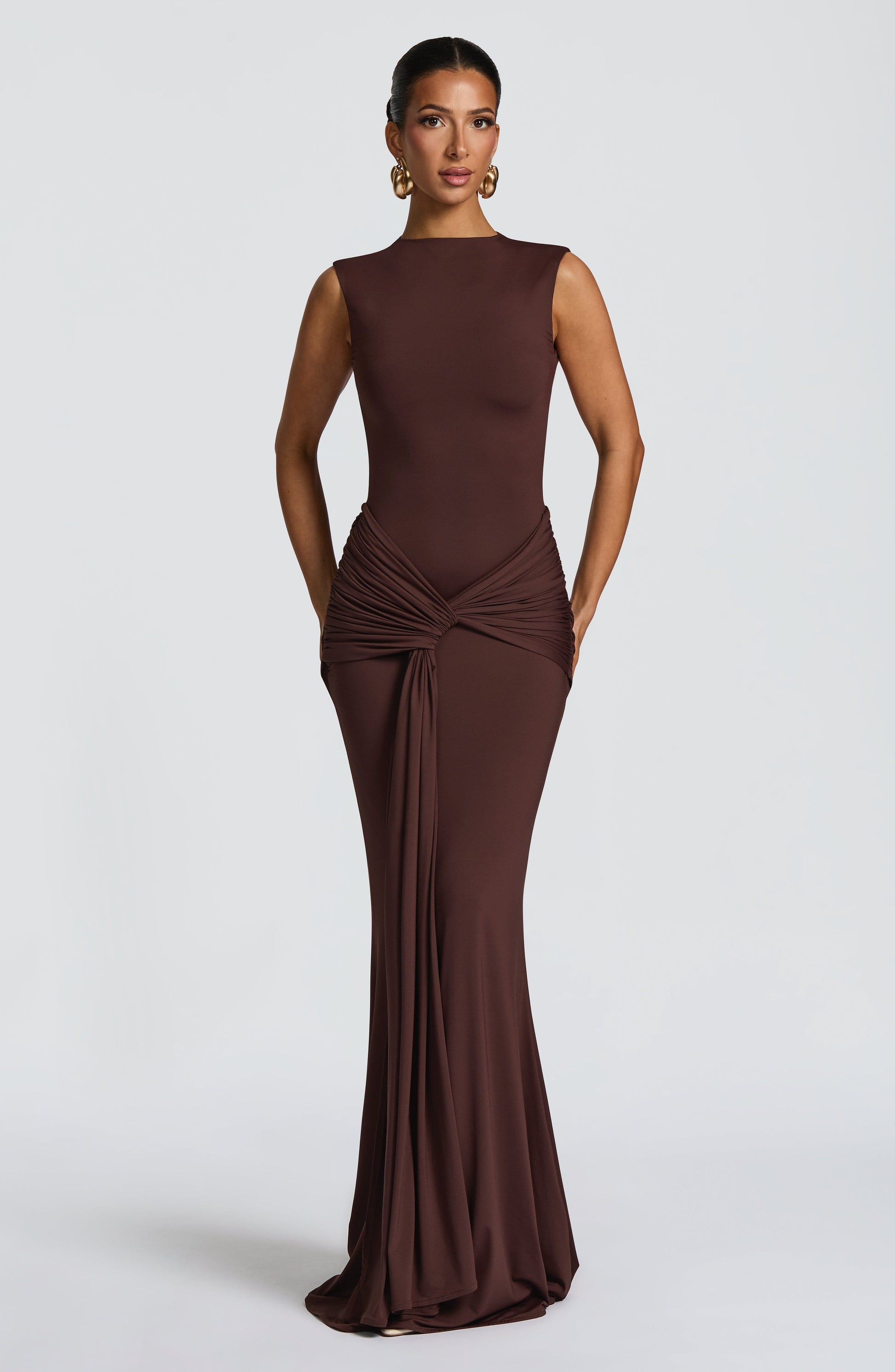 Chocolate brown sleeveless maxi dress with ruched waist knot and long draped front panel, bodycon fit