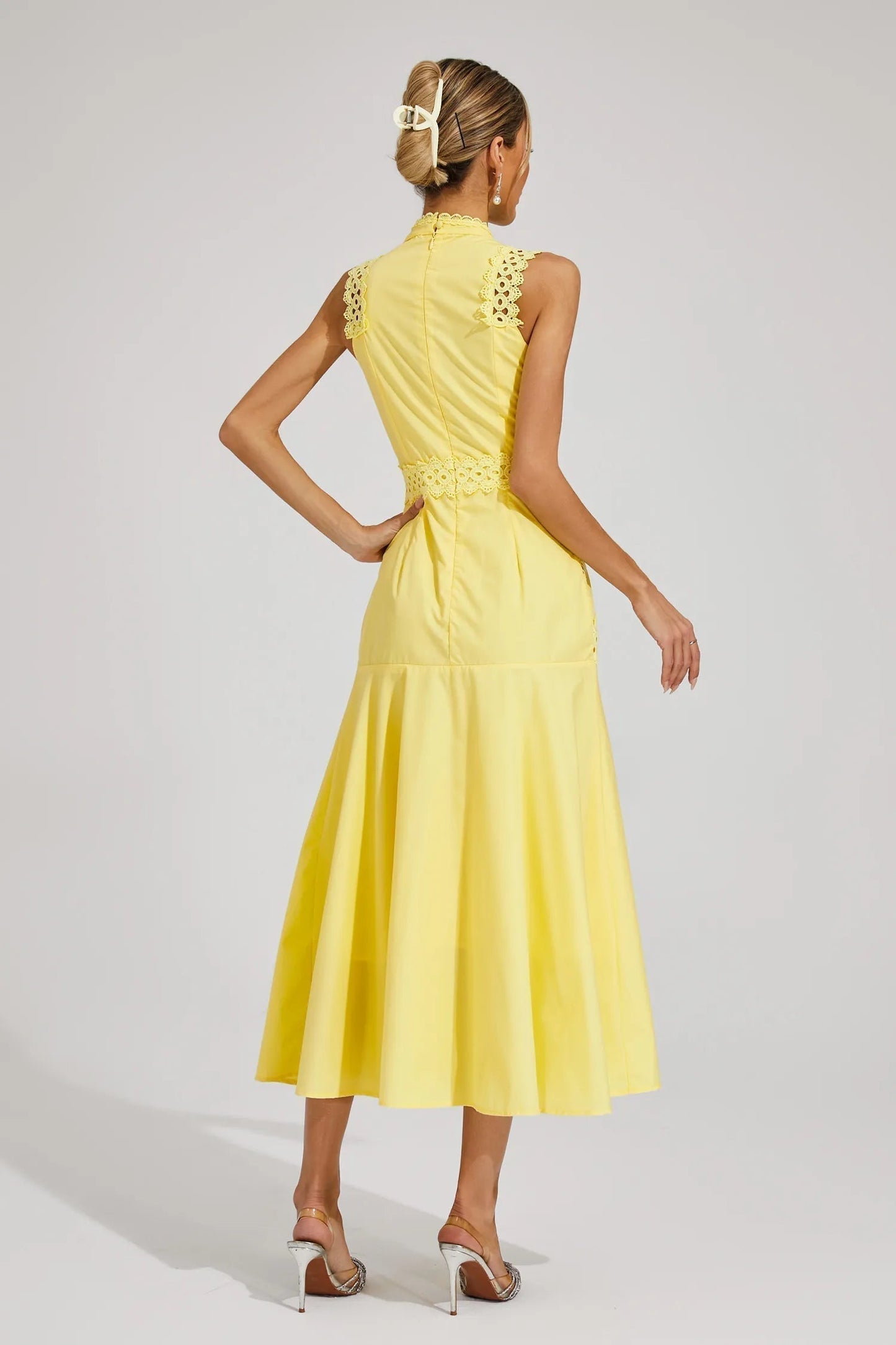 Back view of the yellow sleeveless midi dress, highlighting the high neck and pleated details on the upper back.