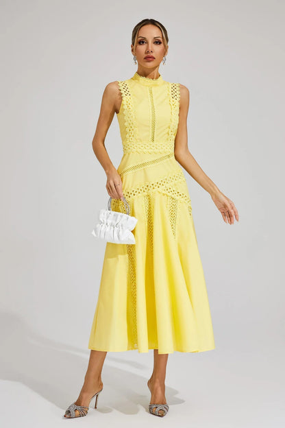 Front view of a yellow sleeveless cutwork midi dress, styled with a white ruched handbag, perfect for vacation dresses.
