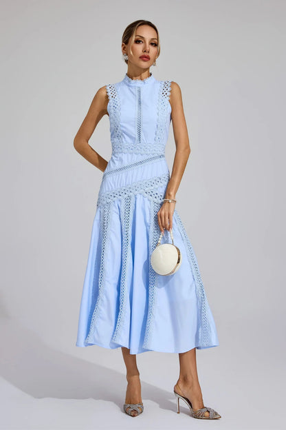 Light blue sleeveless cutwork high neck midi dress, ideal as a beach dress for women or a vacation outfit, styled with a round white bag.