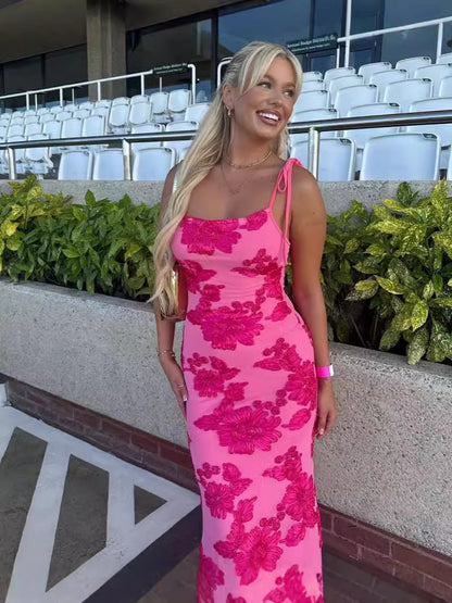 Pink bodycon floral maxi dress with embroidered flowers and tie straps, outdoor event seating background
