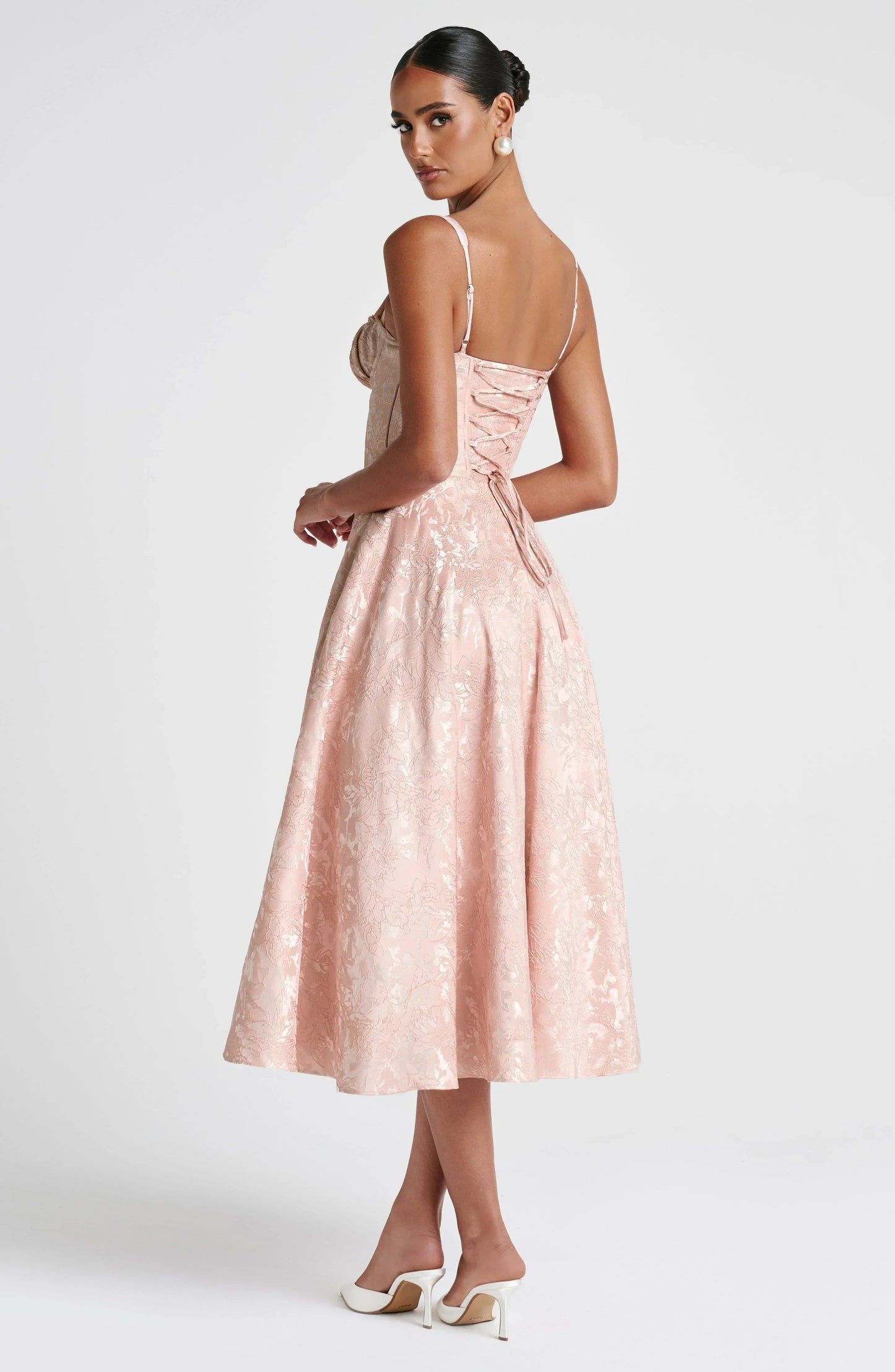 Back angled view blush floral midi dress with lace-up corset back detail, wide straps, and full skirt