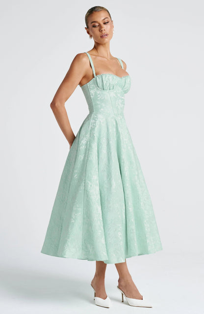 Side view mint green wedding guest midi dress with square neckline, wide straps, and flared jacquard skirt