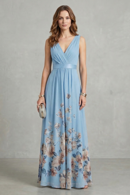 Full-length view of a woman wearing a light blue floral V-neck maxi dress with a pleated waist, suitable as a wedding guest dress.